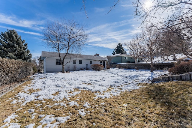 snow covered rear of property featuring a chimney