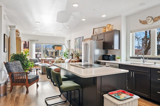 kitchen featuring black appliances, open floor plan, a sink, and light countertops