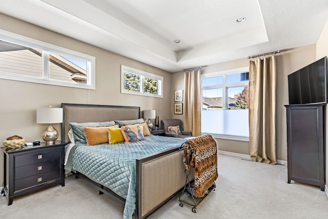 bedroom with baseboards, a raised ceiling, and light colored carpet