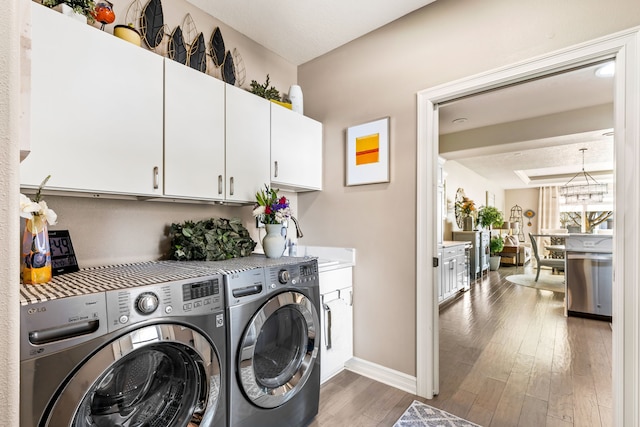 laundry room featuring cabinet space, washing machine and dryer, baseboards, and wood finished floors