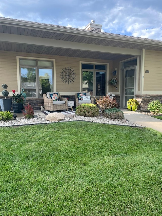 entrance to property with covered porch, a lawn, and an outdoor living space