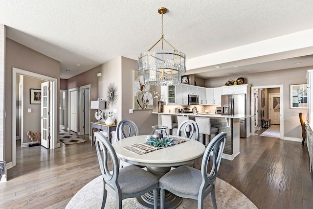 dining area with baseboards, hardwood / wood-style floors, an inviting chandelier, a textured ceiling, and recessed lighting