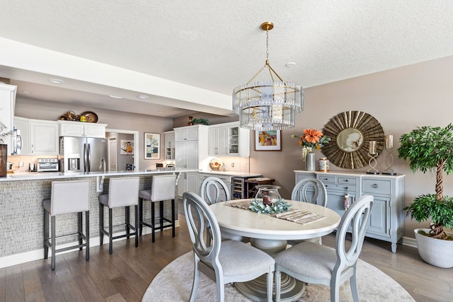 dining space with a toaster, a notable chandelier, dark wood finished floors, and a textured ceiling