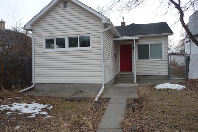 view of front of home featuring entry steps, a chimney, fence, and roof with shingles