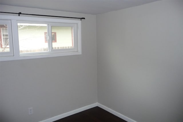 spare room featuring dark wood finished floors and baseboards