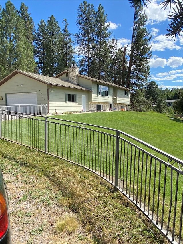 view of front of property featuring a front yard, a chimney, an attached garage, and fence private yard