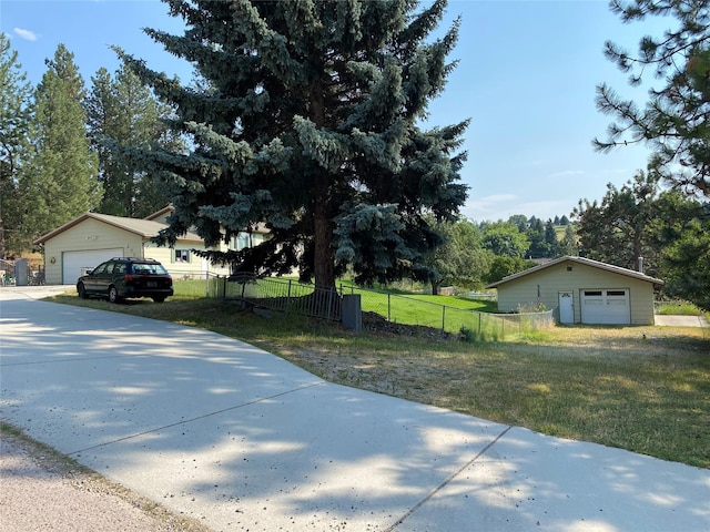 view of side of home with a detached garage, fence, a lawn, and an outbuilding