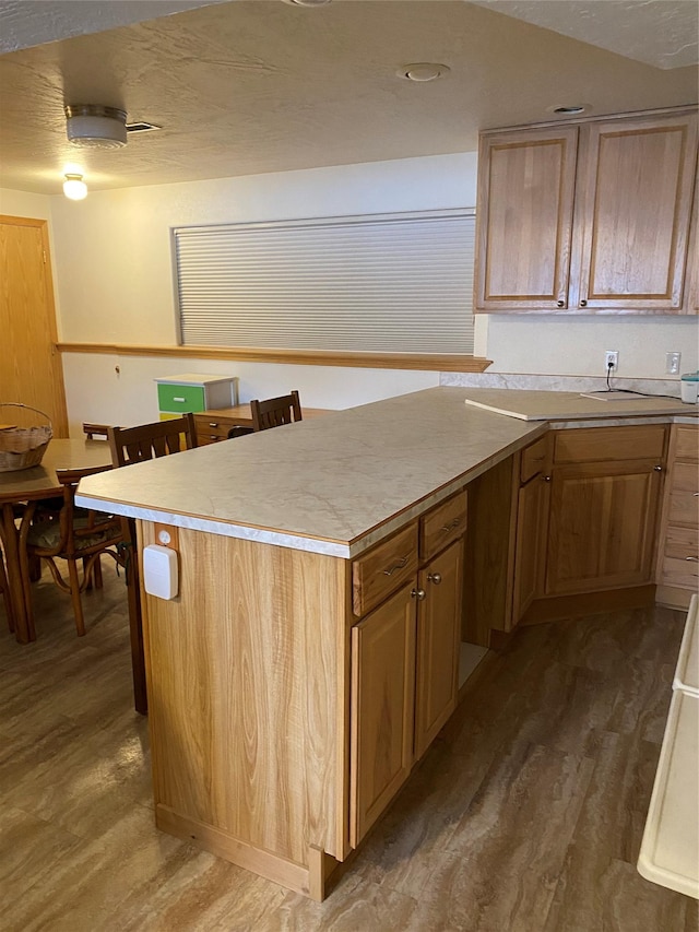 kitchen featuring light countertops, a peninsula, a breakfast bar area, and wood finished floors