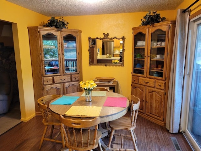 dining space with a textured ceiling, dark wood-style flooring, visible vents, and baseboards