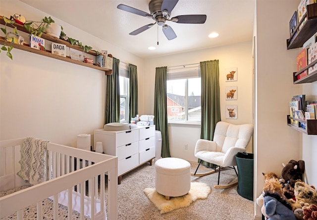 carpeted bedroom with recessed lighting, ceiling fan, and a crib