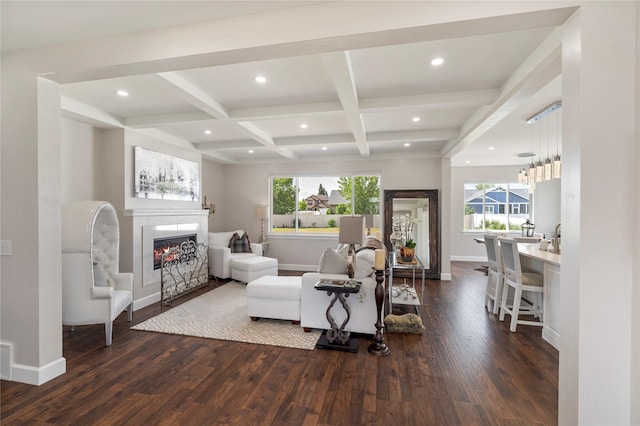 living area with a tiled fireplace, dark wood finished floors, beam ceiling, and a healthy amount of sunlight