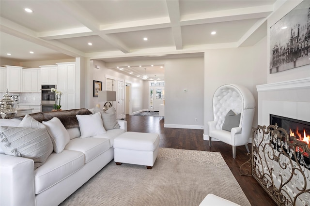 living area featuring dark wood-style floors, coffered ceiling, beamed ceiling, a lit fireplace, and baseboards