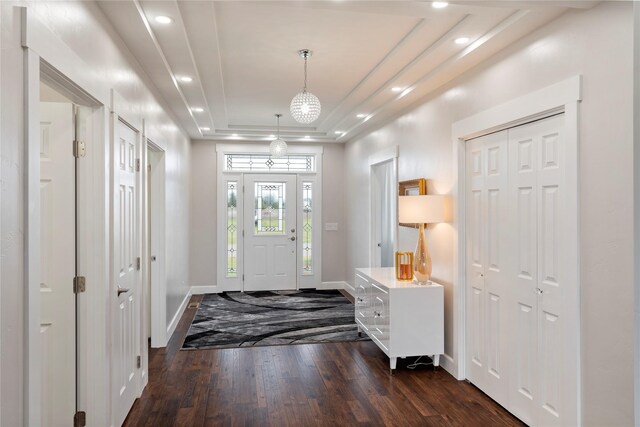 foyer entrance with dark wood-type flooring, recessed lighting, a raised ceiling, and baseboards