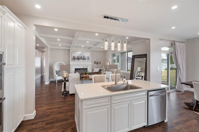 kitchen featuring a fireplace, a sink, white cabinets, dishwasher, and an island with sink