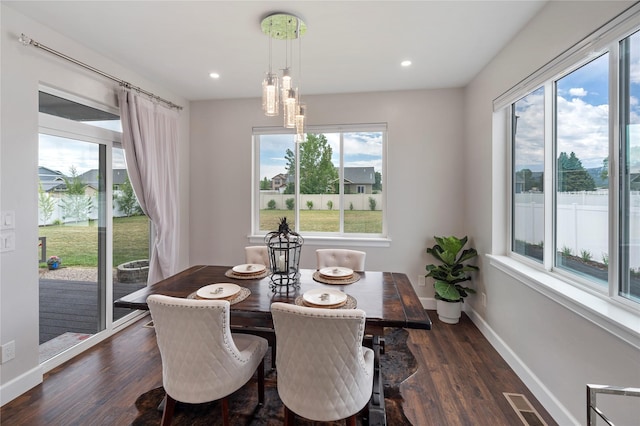 dining area with a healthy amount of sunlight, dark wood finished floors, visible vents, and baseboards