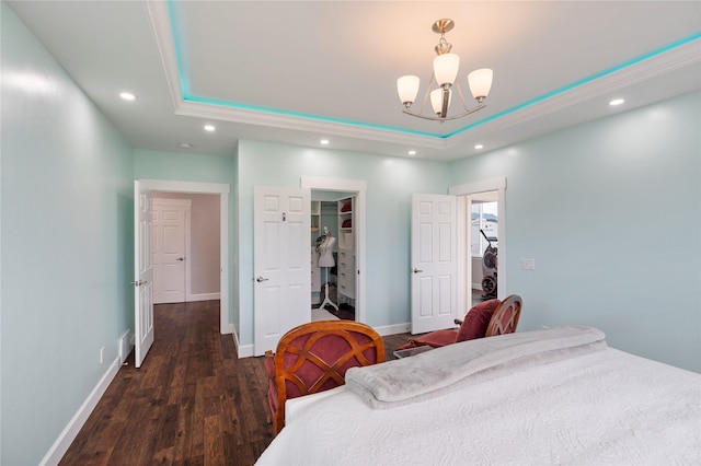 bedroom featuring a walk in closet, recessed lighting, a raised ceiling, wood finished floors, and baseboards