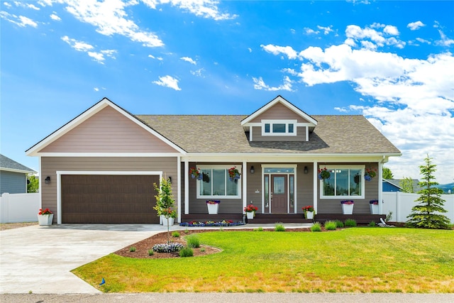 view of front of property featuring a front lawn, concrete driveway, fence, and an attached garage