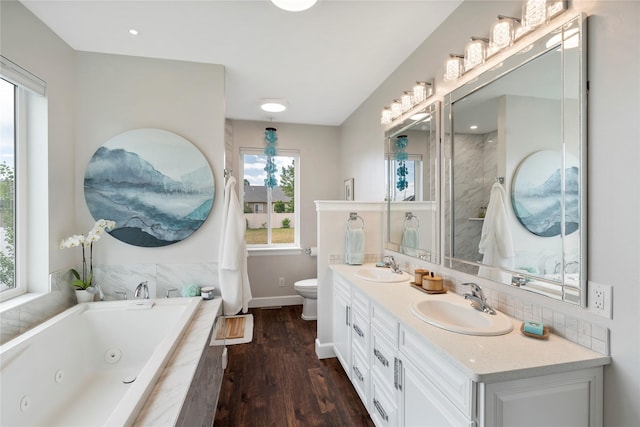 full bathroom with toilet, a sink, a whirlpool tub, and wood finished floors