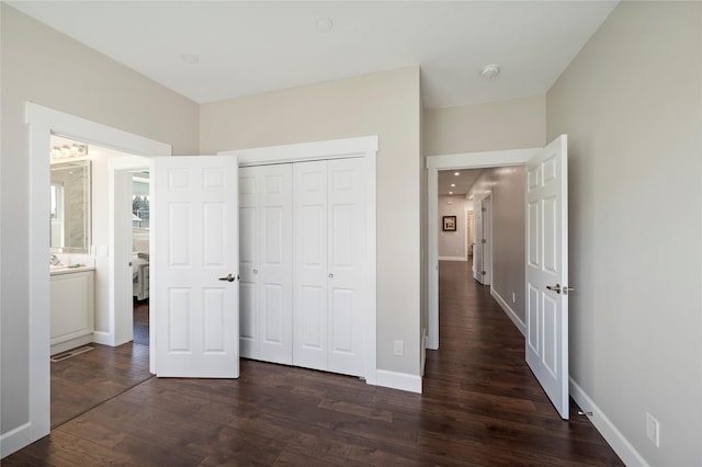 unfurnished bedroom featuring dark wood-type flooring, a closet, and baseboards