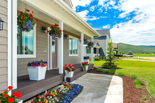 entrance to property with covered porch and a yard