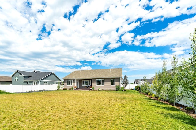 rear view of house featuring a lawn and fence