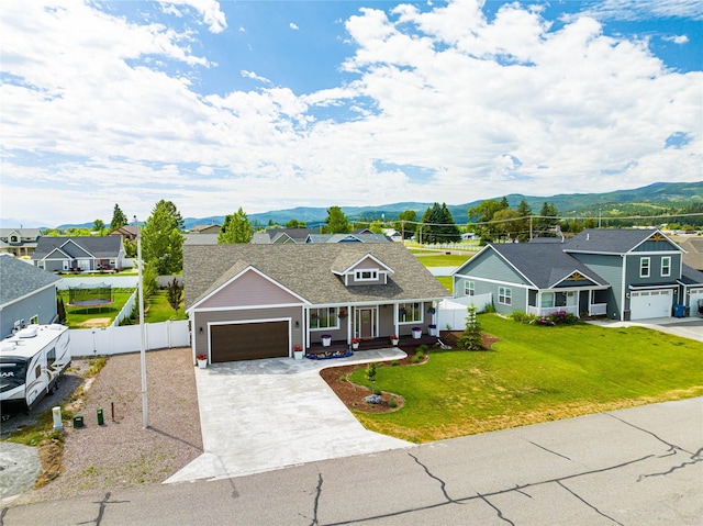 view of front of property with covered porch, a front yard, a mountain view, fence, and a residential view