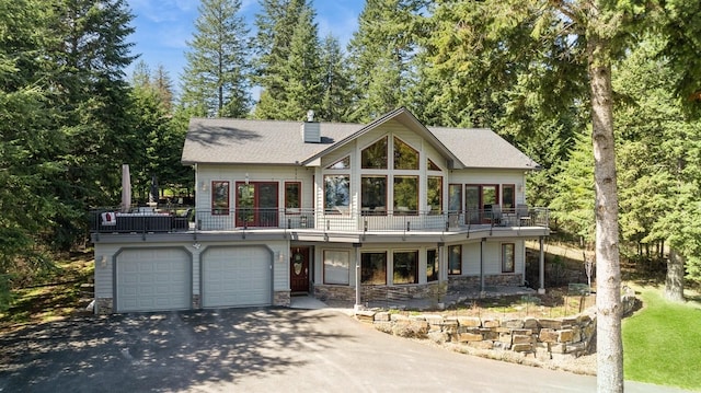 156 Wulff Ln, Lakeside, MT 59922 - view of front of property featuring driveway, stone siding, an attached garage, and a balcony