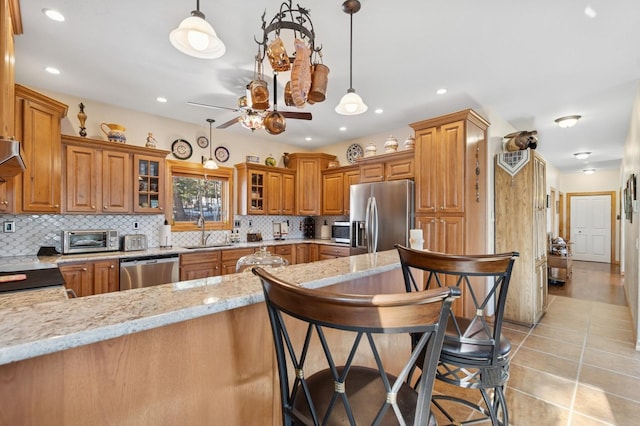 156 Wulff Ln, Lakeside, MT 59922 - kitchen featuring appliances with stainless steel finishes, a sink, brown cabinets, decorative backsplash, and ceiling fan
