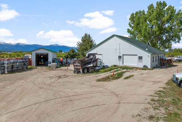 245 Olde Rd, Hamilton, MT 59840 - view of side of home with a garage, a mountain view, and an outbuilding