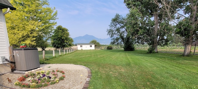 view of yard featuring a storage unit, fence, an outdoor structure, a mountain view, and central AC