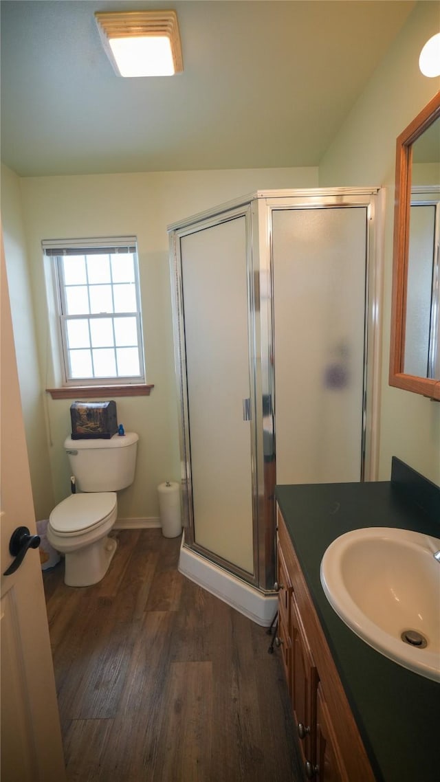 bathroom with a stall shower, baseboards, toilet, wood finished floors, and vanity