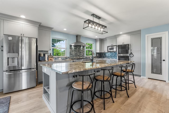 245 Olde Rd, Hamilton, MT 59840 - kitchen with stainless steel appliances, wall chimney range hood, light stone counters, tasteful backsplash, and recessed lighting