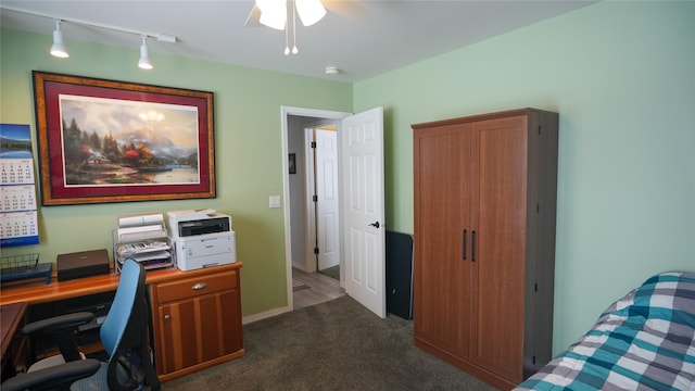 carpeted home office featuring rail lighting, ceiling fan, and baseboards