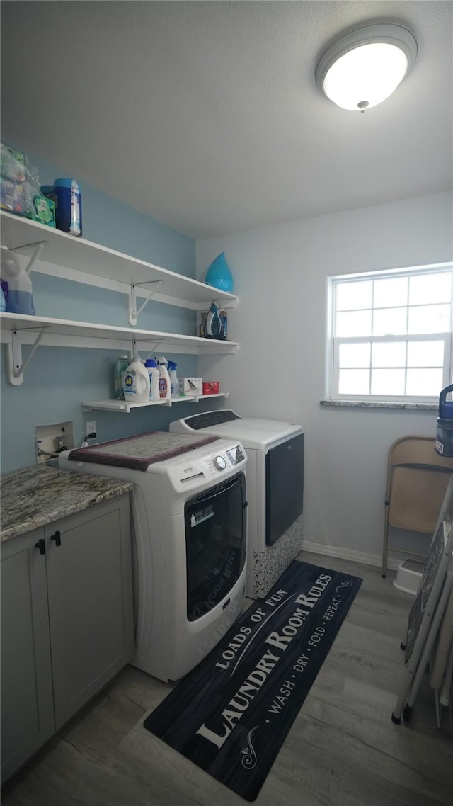 washroom with separate washer and dryer, light wood-type flooring, cabinet space, and baseboards