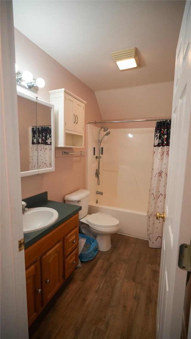 bathroom featuring lofted ceiling, toilet, wood finished floors, vanity, and shower / bath combination with curtain