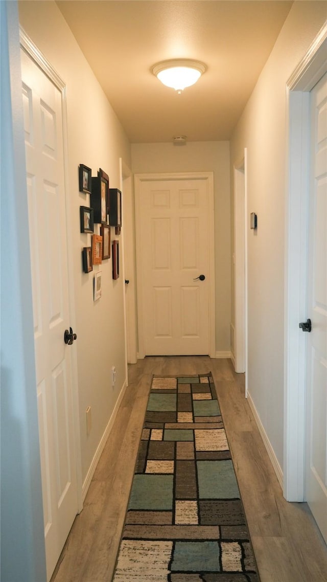 hallway featuring baseboards and wood finished floors