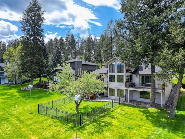 rear view of house with fence, a lawn, and a wooden deck