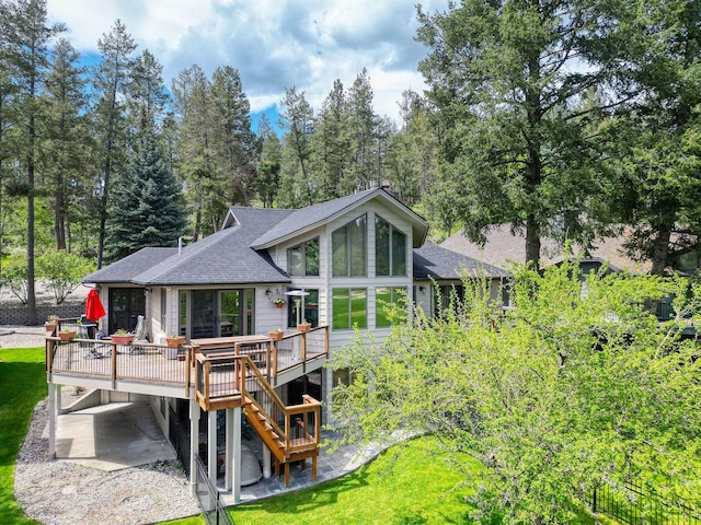 99 Golf Ter, Bigfork, MT 59911 - back of house with a deck, a carport, a sunroom, a shingled roof, and stairway