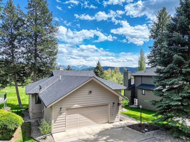 99 Golf Ter, Bigfork, MT 59911 - view of front of property featuring a mountain view, a chimney, driveway, a shingled roof, and a garage