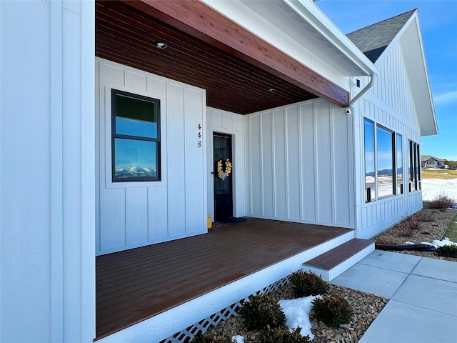 view of exterior entry featuring roof with shingles and board and batten siding