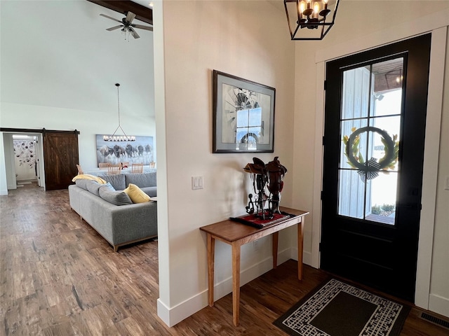 entryway featuring a barn door, ceiling fan with notable chandelier, wood finished floors, visible vents, and baseboards