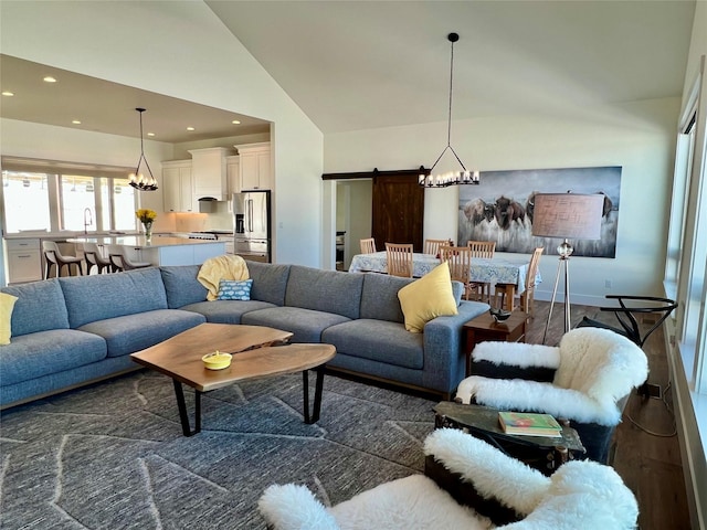 living room featuring an inviting chandelier, a barn door, dark wood-type flooring, and recessed lighting