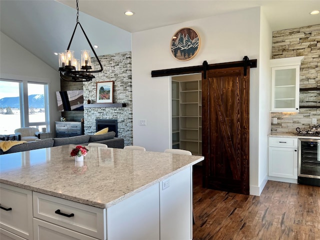 kitchen featuring wine cooler, a fireplace, backsplash, a barn door, and white cabinets