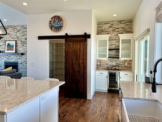 kitchen featuring dark wood-style floors, backsplash, a barn door, white cabinetry, and beverage cooler