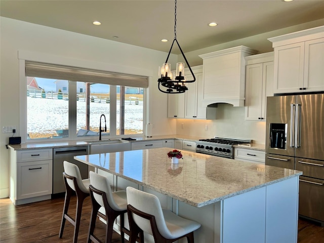 kitchen with dark wood-type flooring, a sink, high quality appliances, and a center island