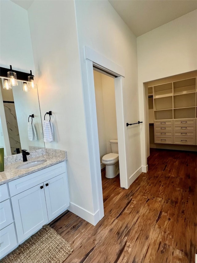 bathroom featuring vanity, wood finished floors, toilet, and baseboards