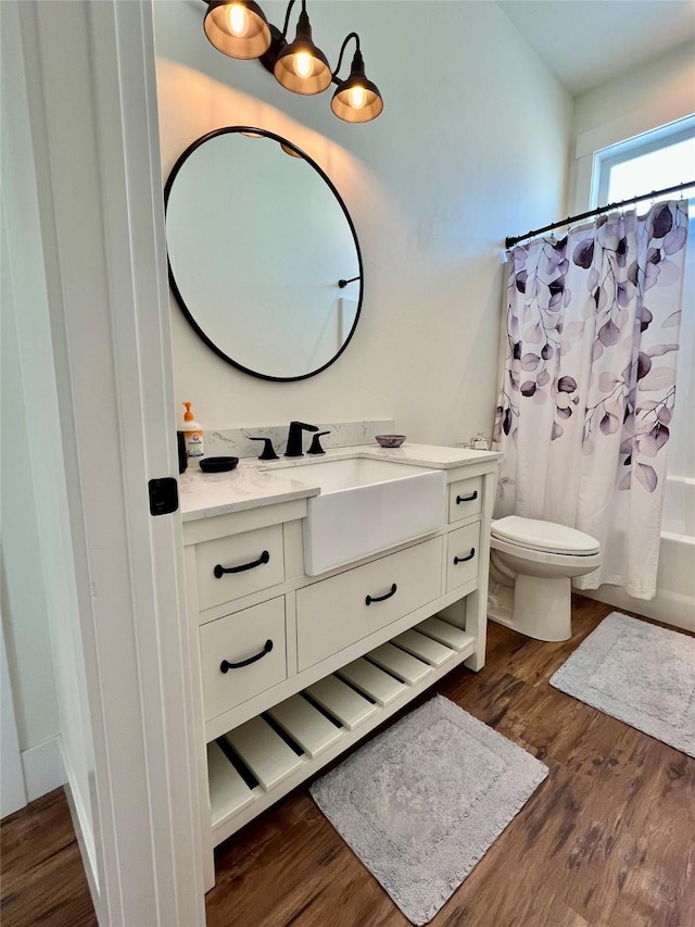 bathroom with toilet, shower / tub combo, wood finished floors, and vanity