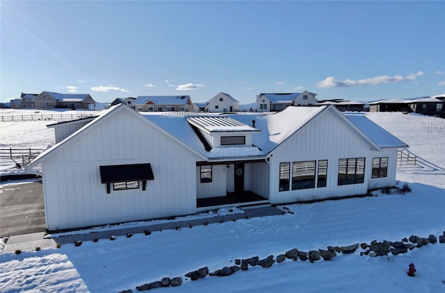 modern farmhouse style home with board and batten siding, metal roof, and fence