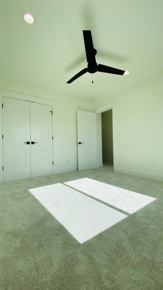 unfurnished bedroom with light carpet, a ceiling fan, and a closet