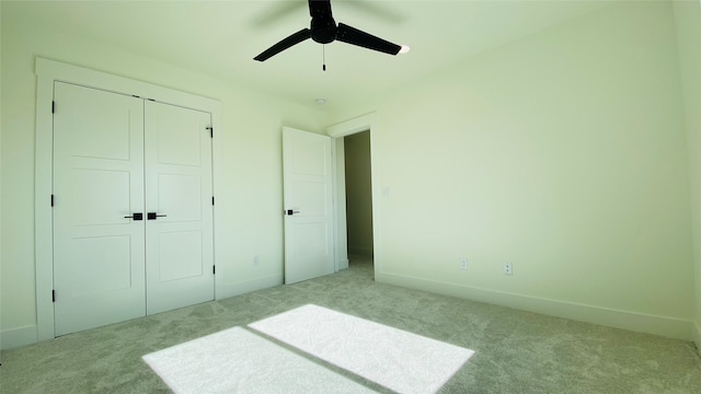 unfurnished bedroom featuring baseboards, ceiling fan, a closet, and light colored carpet